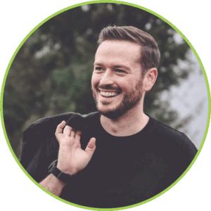 Profilbild Benjamin Schäfer mit schwarzem Shirt und umgehängter Jacke in der Natur im Hintergrund mit Bäumen