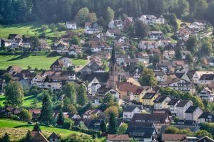 Kleines Dorf in den Bergen in Deutschland Blick auf ein kleines Dorf in Deutschland welches in den Bergen und im Grünen liegt, in der Mitte ist ein Kirchturm zu sehen.